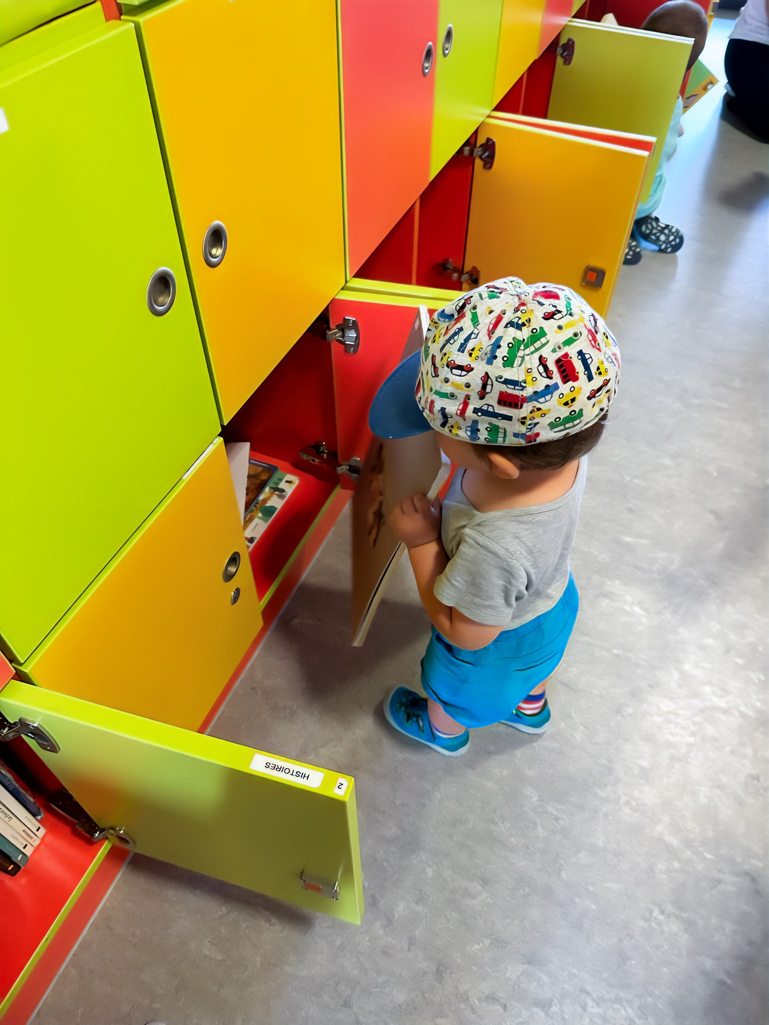un enfant qui prend un livre dans la bibliothèque partagée de notre crèche Atrium située à Bertrange au Luxembourg