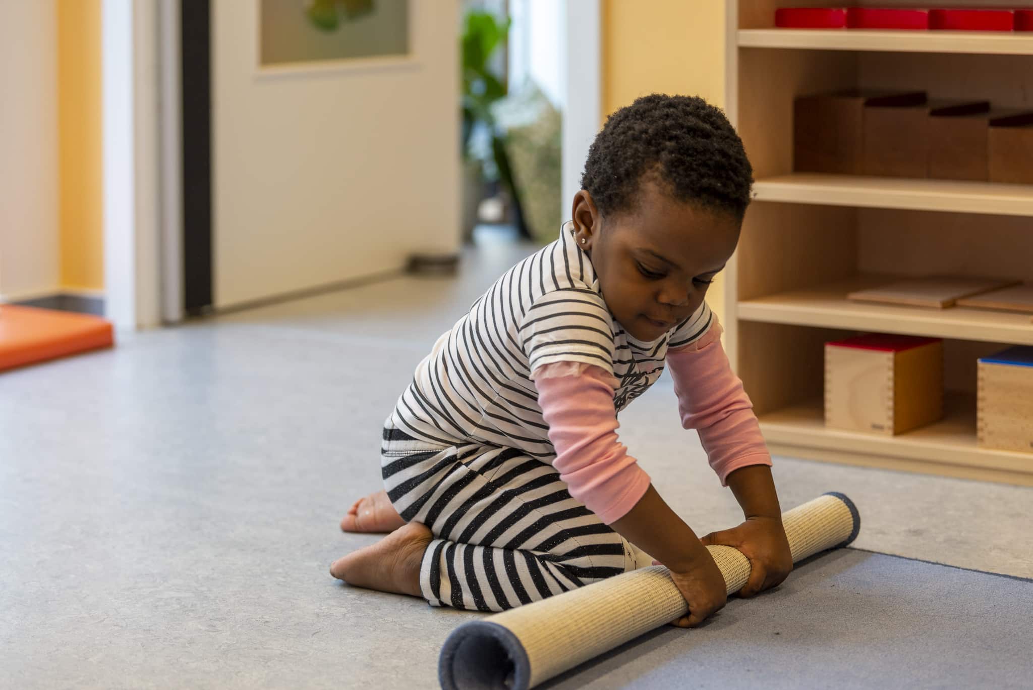 enfant qui roule un tapis pour une activité Montessori en crèche du Luxembourg