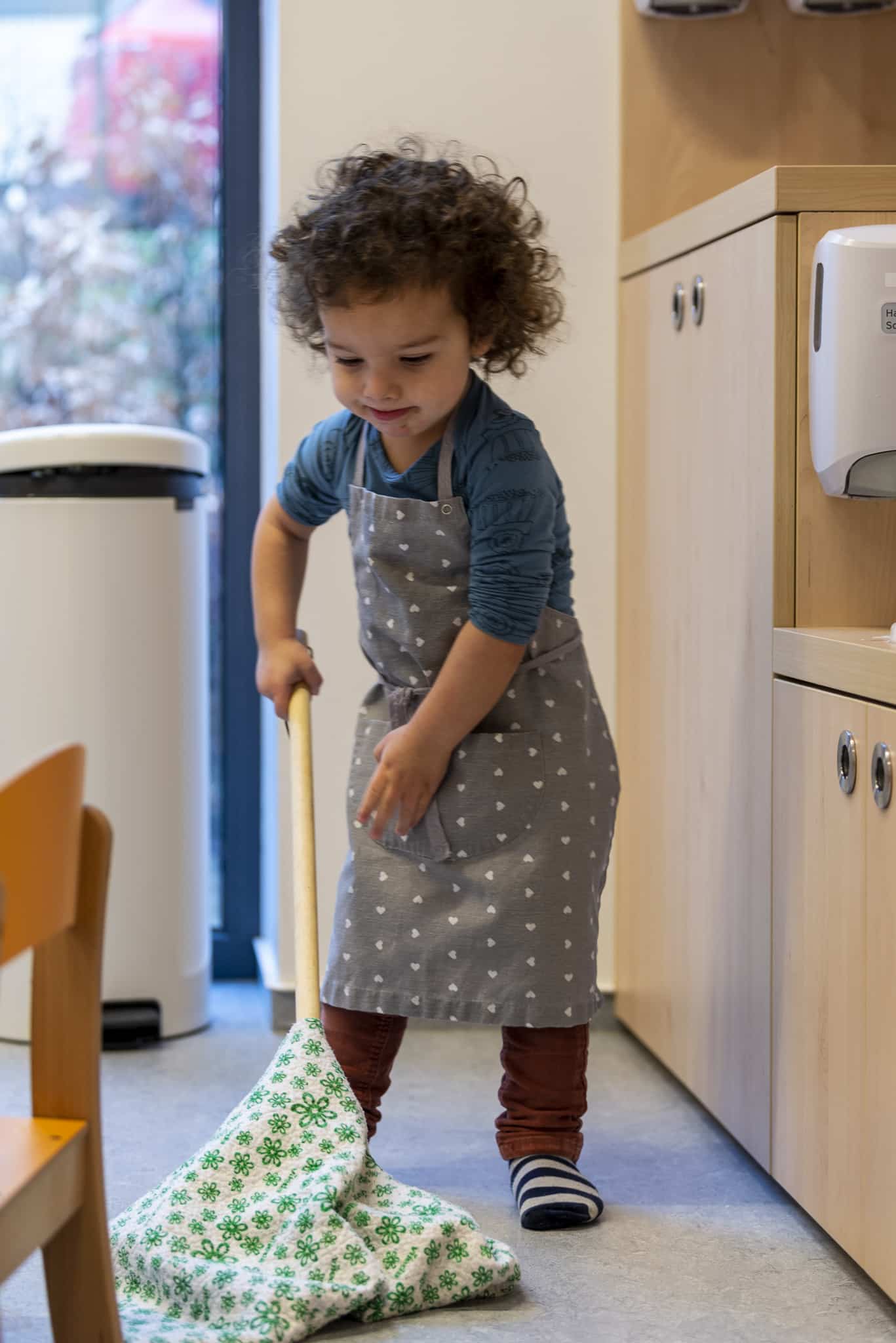 enfant qui passe le balai pour une activité Montessori en crèche du Luxembourg