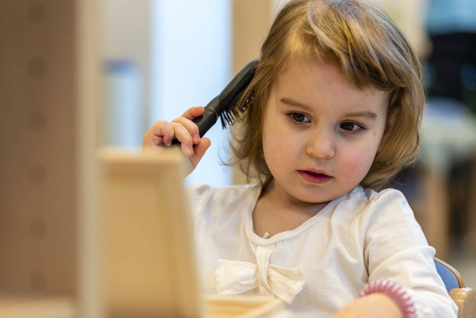 enfant qui se coiffe pour une activité Montessori en crèche du Luxembourg