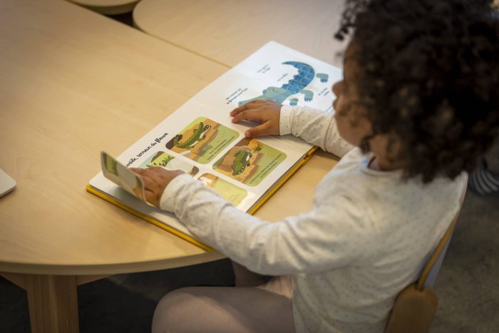 un enfant lit un livre en crèche