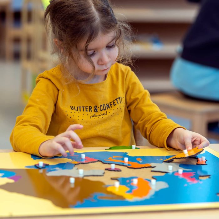 un enfant fait un puzzle du monde montessori en crèche