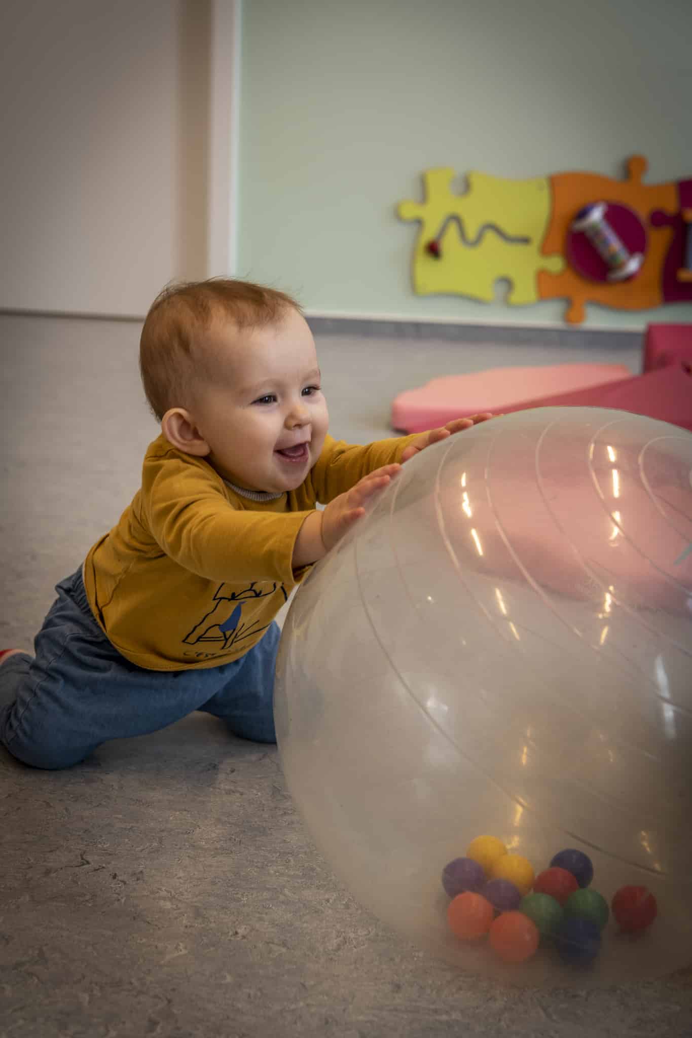 un bébé joue avec une balle de gym à la crèche