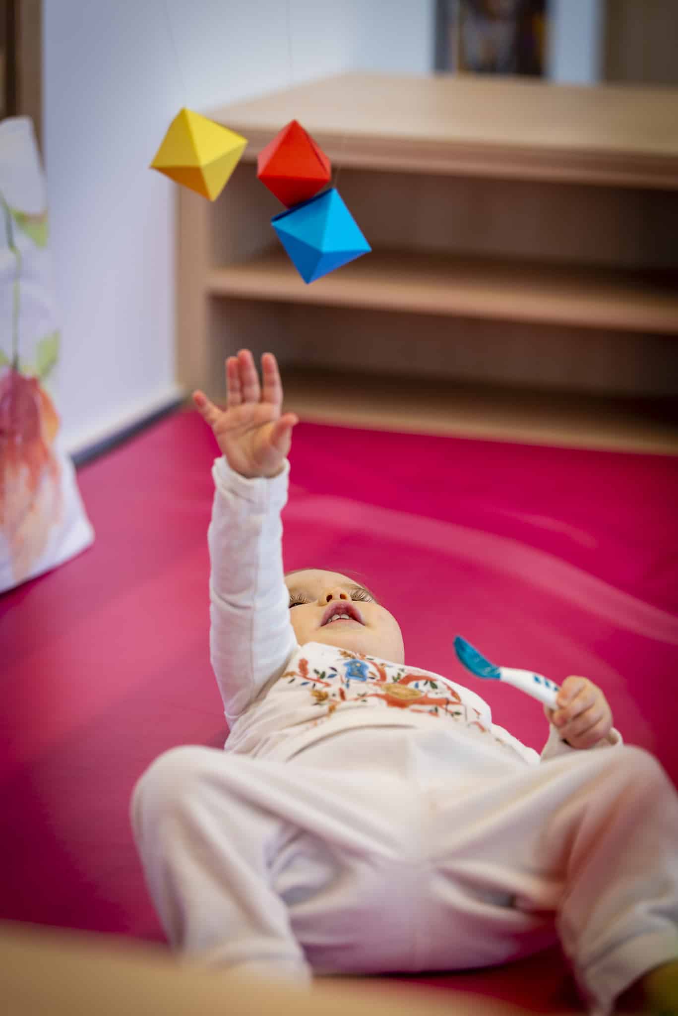 un enfant joue avec un mobile montessori en crèche
